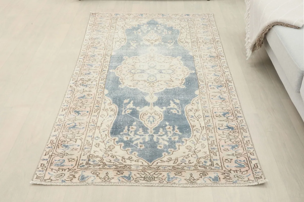 Full overhead view of the blue and ivory rug laid out on a light-colored floor in a room setting
