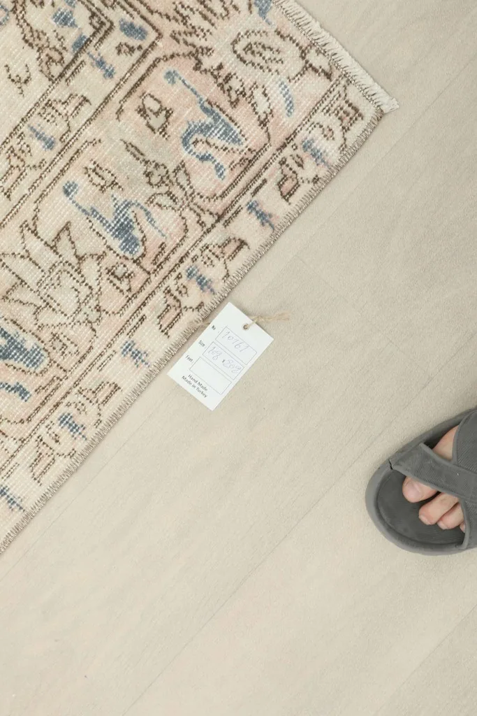 Overhead view showing the rug's texture and a small tag, with a foot in a sandal for scale