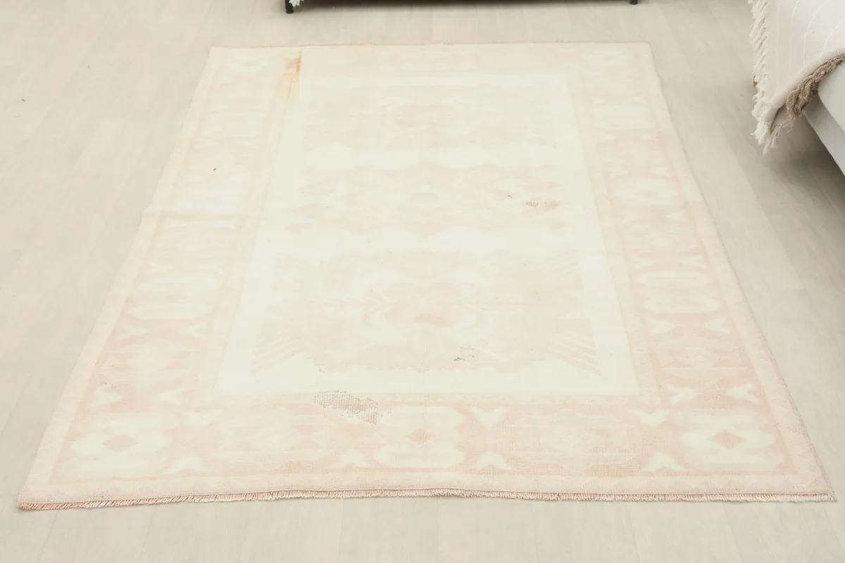 Full room view of the 4'9" x 6'11" cream and rose vintage Anatolian rug, showcasing its small size.