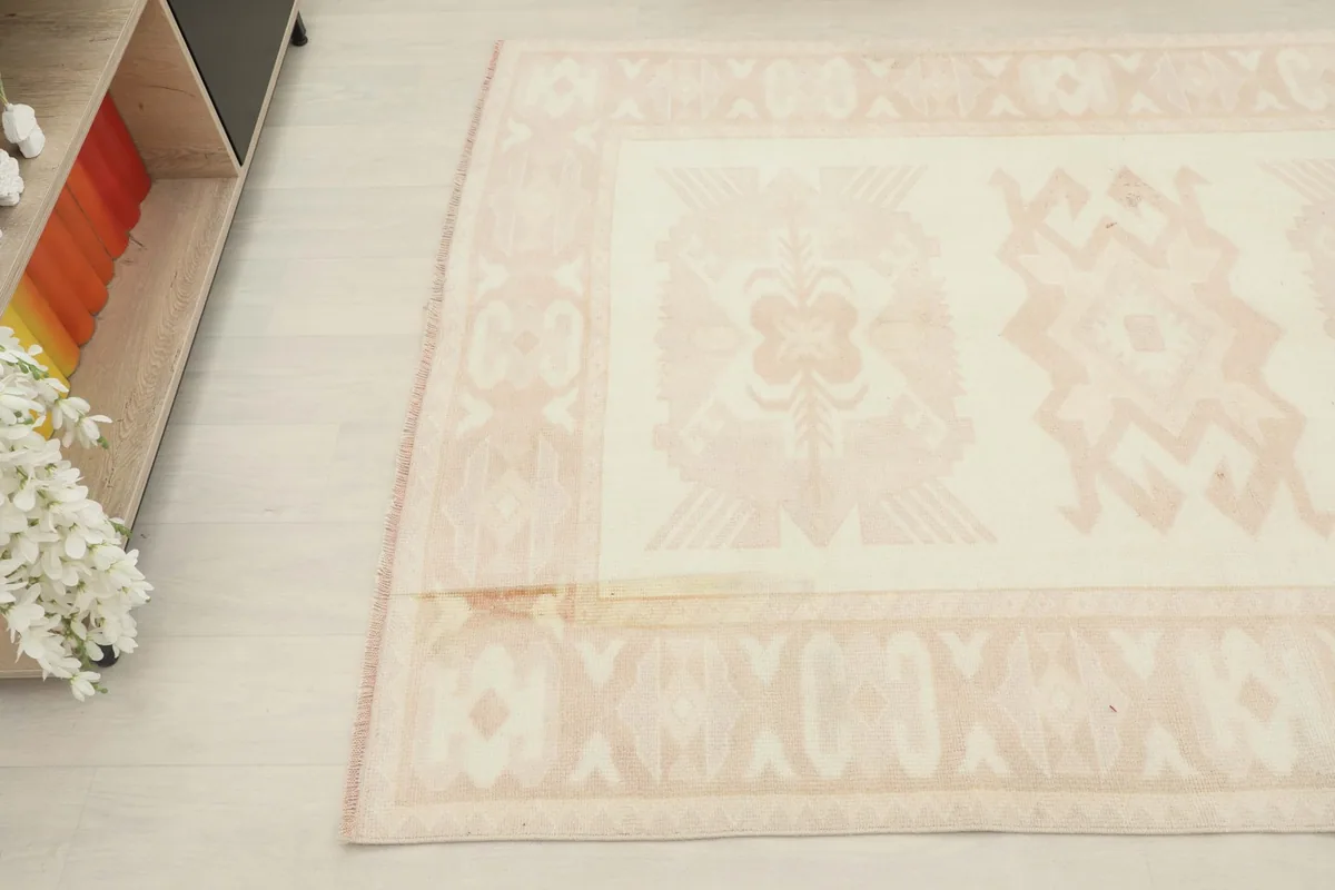 Overhead detail of a section of the rug, showing the blend of cream and rose colors and subtle patterns.