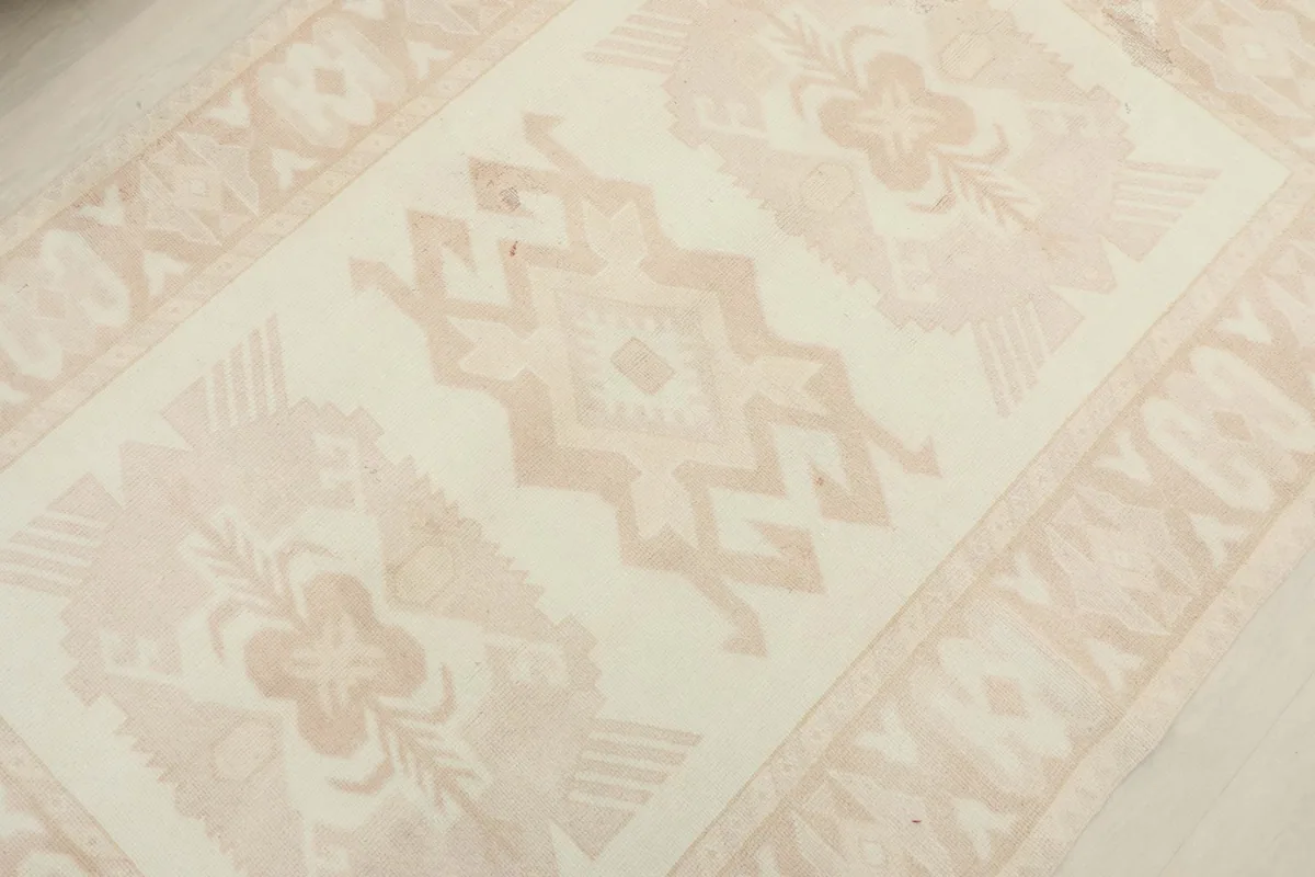 Overhead view focusing on the central geometric motifs and the overall faded appearance of the rug.