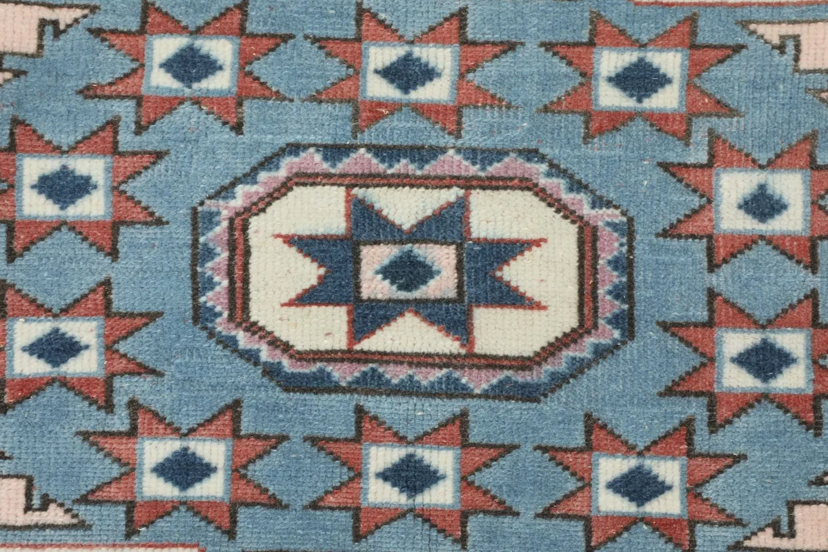 Detailed close-up of a blue geometric medallion with star patterns and subtle rose accents