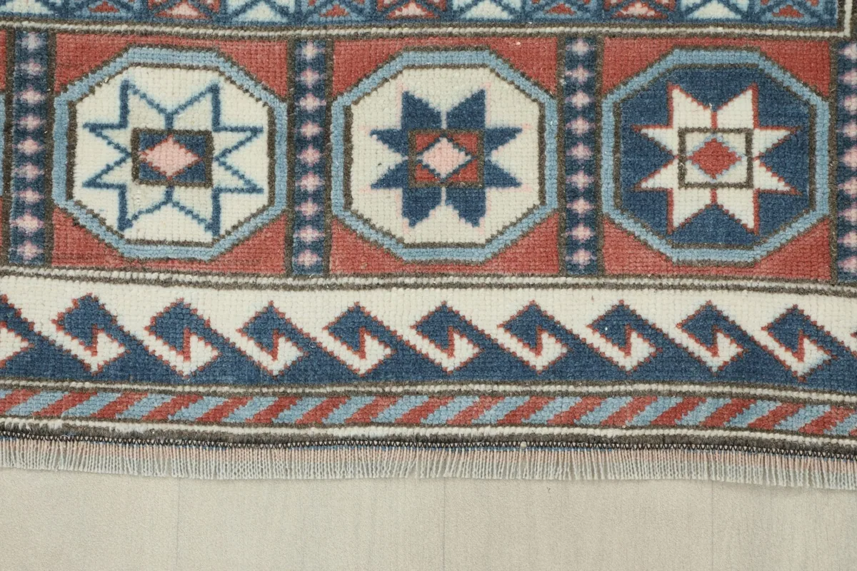 Close-up of the rug's border, featuring wave patterns and octagonal motifs in blue, navy, and rust
