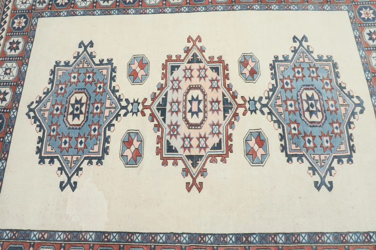Overhead detail of the rug's central medallions, showing variations in the ivory field