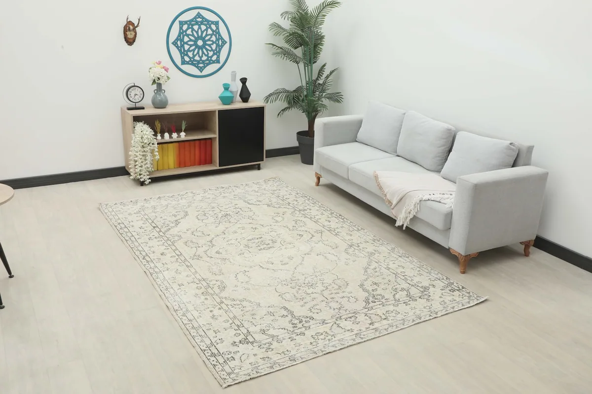 Vintage Anatolian rug in an ivory and gray pattern placed in a living room setting with a light gray sofa