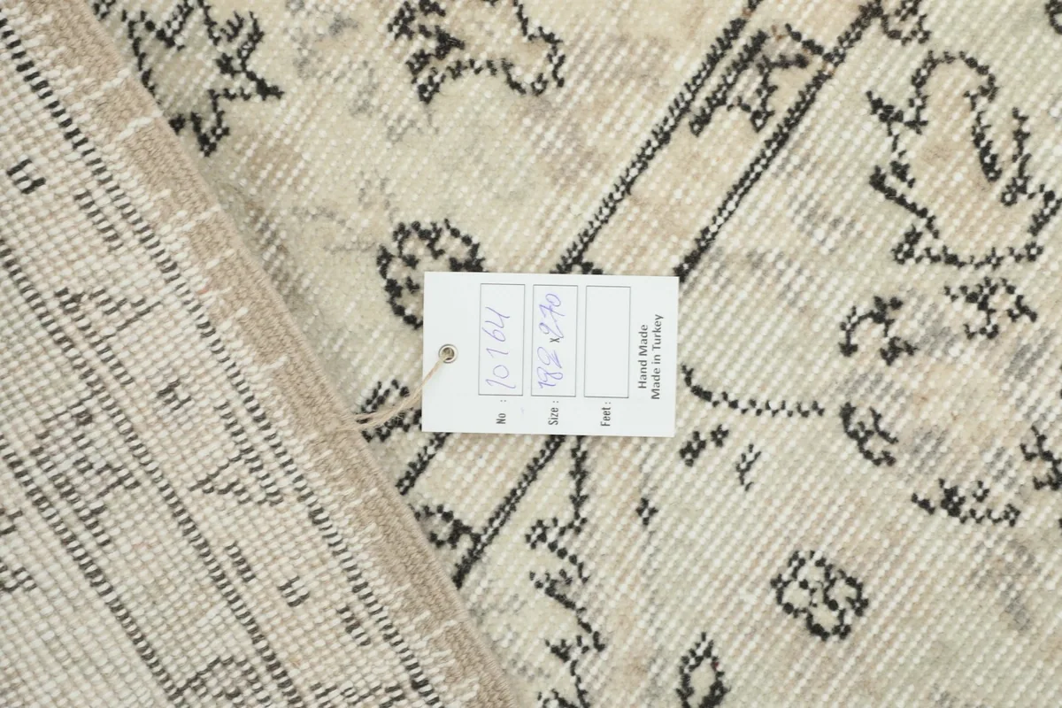 Close-up of the rug's back, displaying the hand-knotted structure and a product tag
