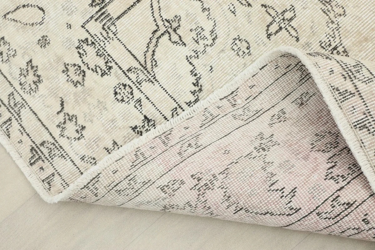 Corner of the rug folded back, revealing the cotton foundation and reverse side of the knotting