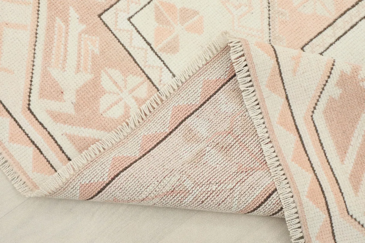 View of the rug's backside and folded edge, revealing the cotton foundation and knotting.