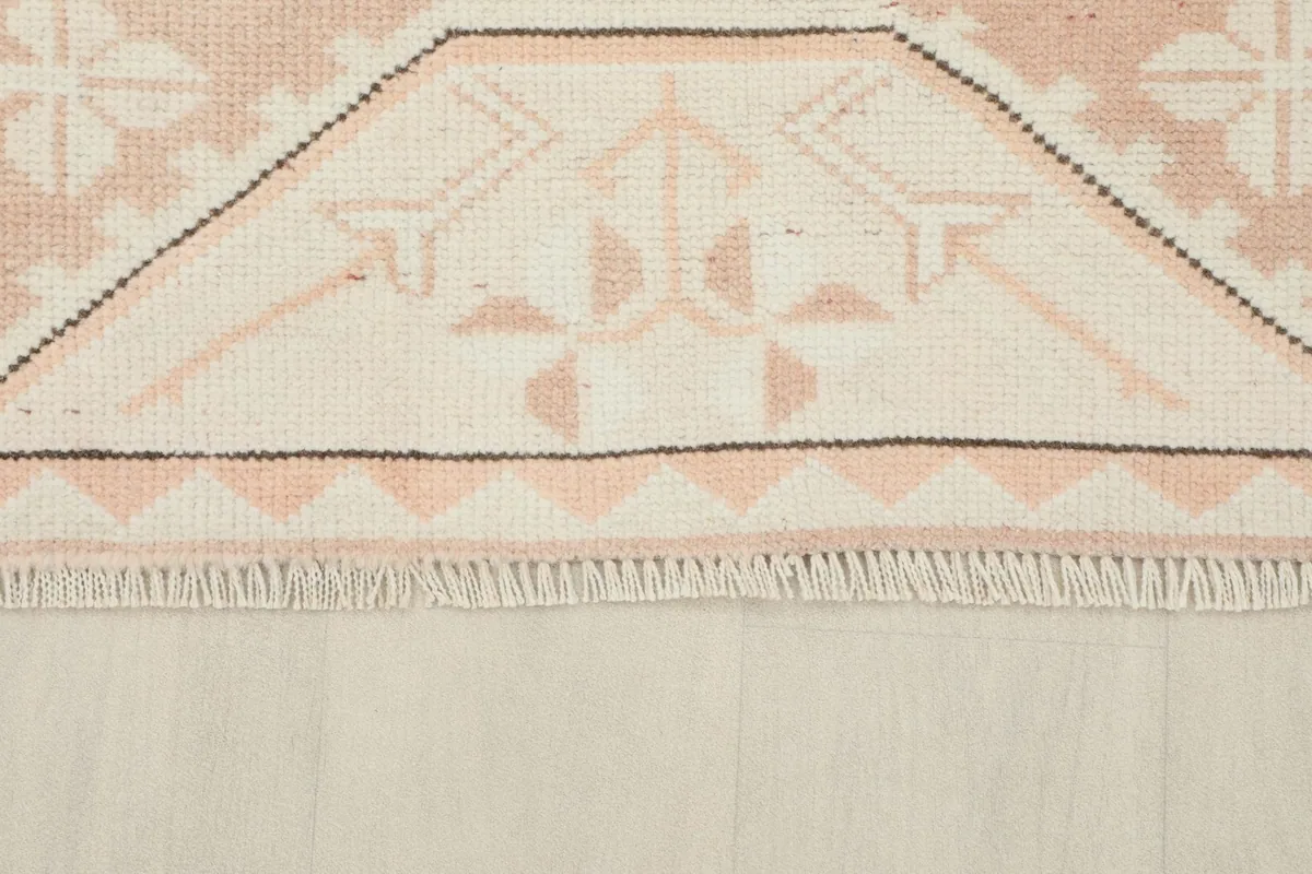 Close-up of the short, natural fringe and the patterned edge of the hand-knotted rug.