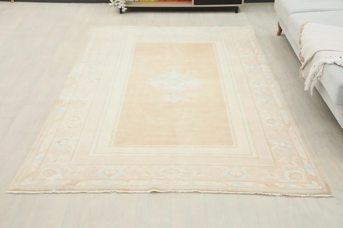 Full overhead view of the beige vintage rug in a room, positioned in front of a sofa.