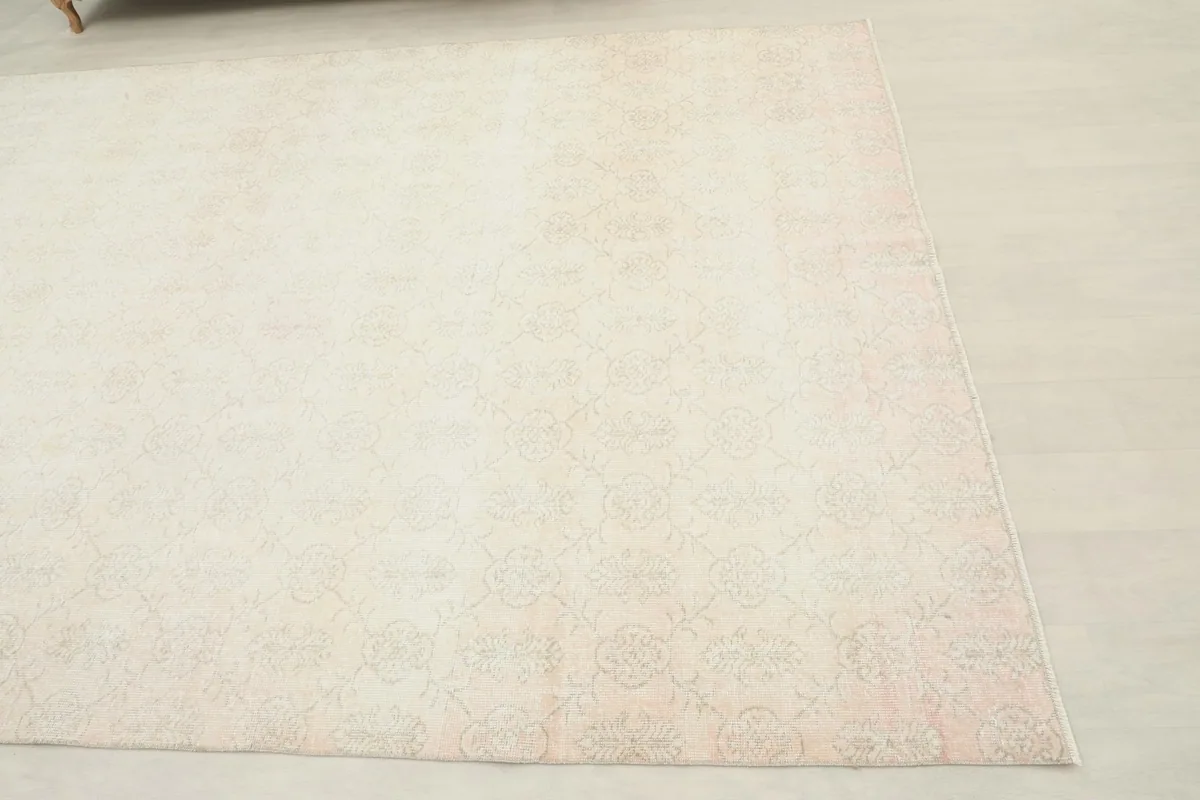 Corner view of the hand-knotted rug, showing the faded rose tones along the edge.