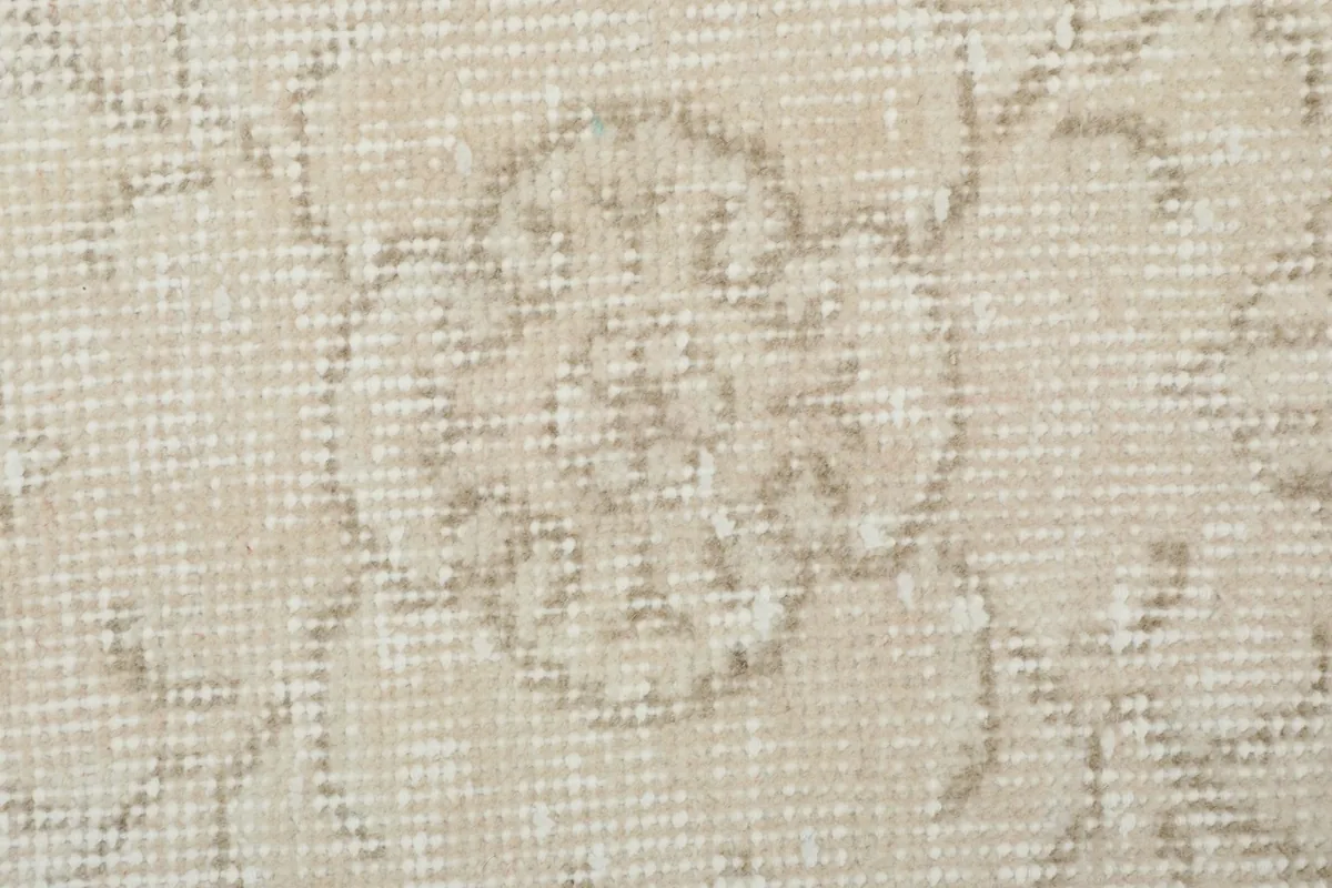 Detailed close-up of the hand-knotted wool pile and a single faded floral motif.