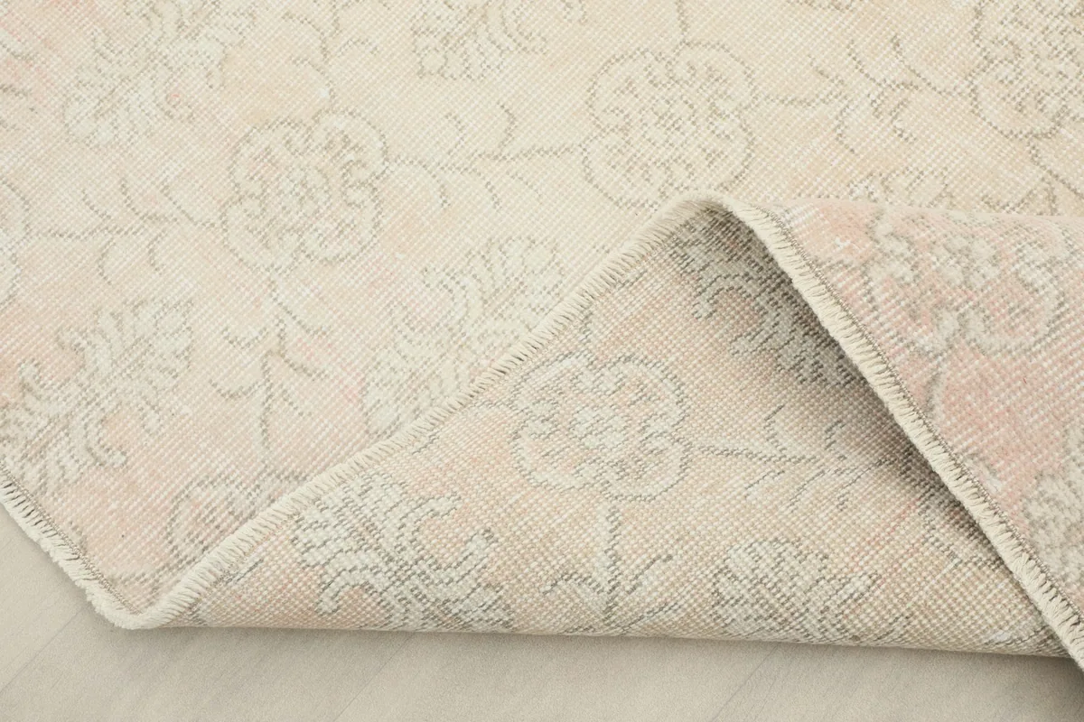 Corner of the rug folded back, revealing the cotton foundation and reverse side of the knotting.