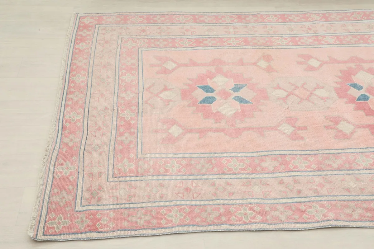 Close-up angled shot of the corner of the pink and blue geometric rug