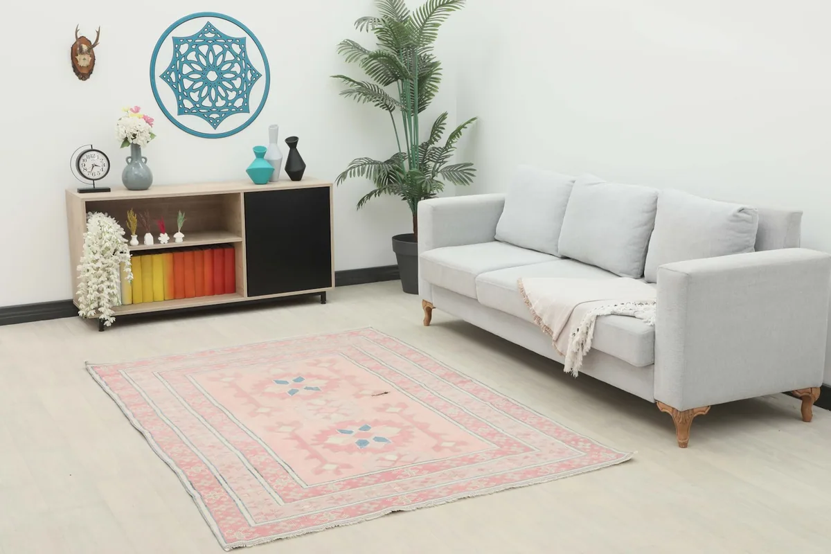 Vintage pink rug displayed in a modern living room setting with a gray sofa