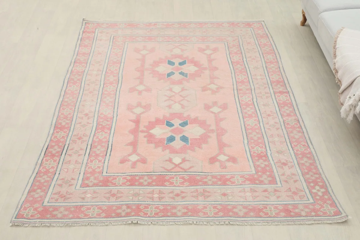Full overhead view of the pink geometric rug in a living room setting next to a sofa