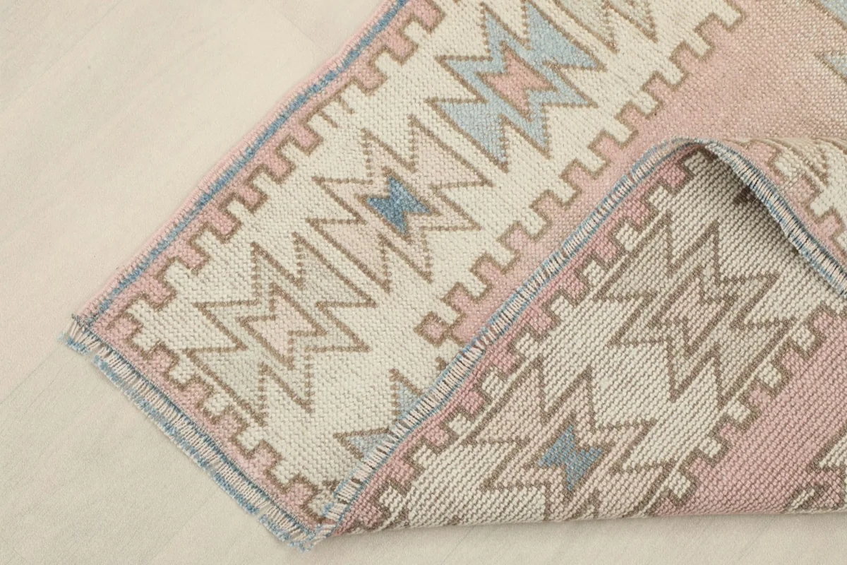 Corner of the rug folded back, showing the back of the hand-knotted wool on cotton foundation