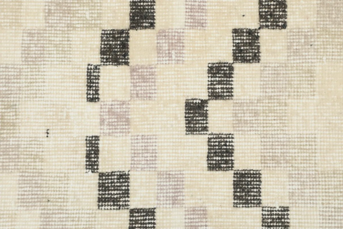 Close-up showing the low wool pile and hand-knotted texture of the ivory and charcoal rug