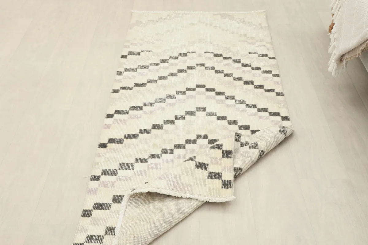 The ivory and charcoal runner rug partially folded, showing its flexibility and thickness
