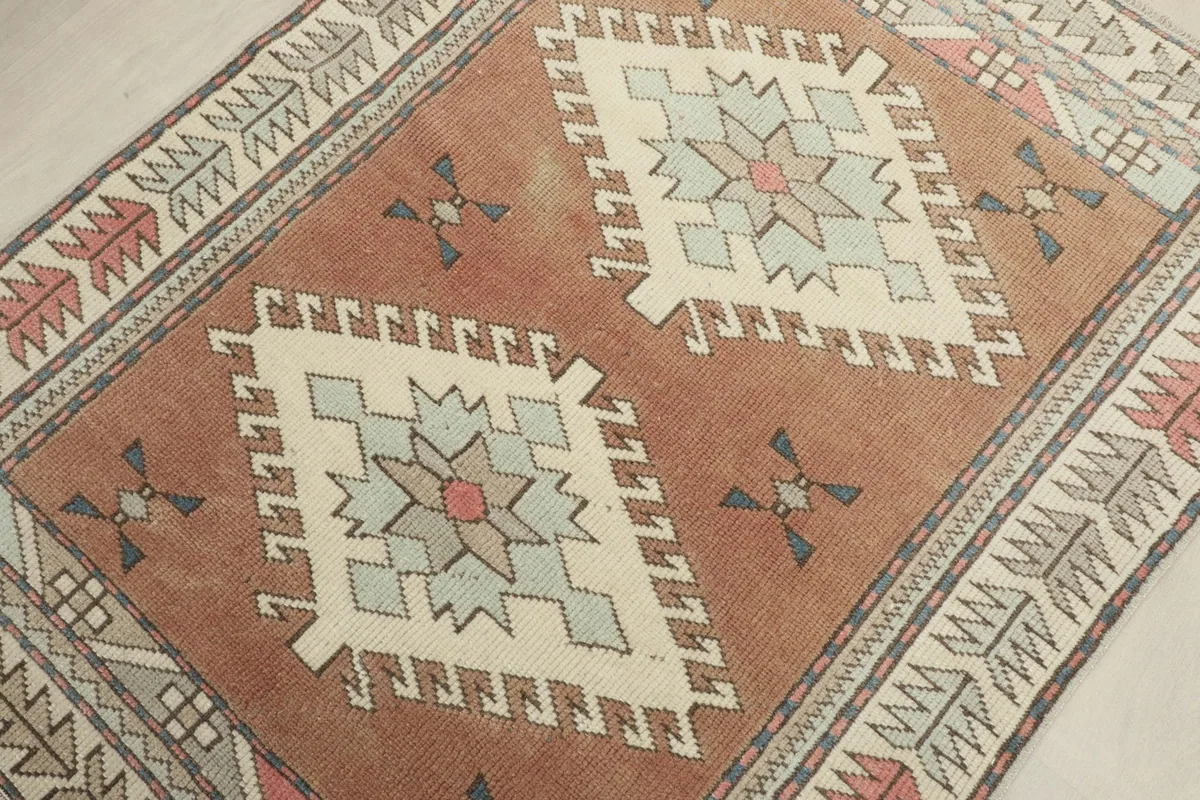 Angled view of the rug's center, focusing on the two cream geometric diamond medallions