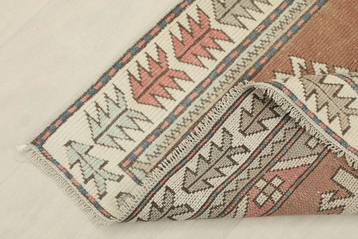 Corner of the rug folded to show the pile texture and the hand-knotted construction