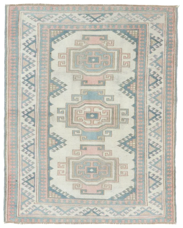 Full top view of the ivory, rose, and blue vintage Anatolian rug with geometric medallions.