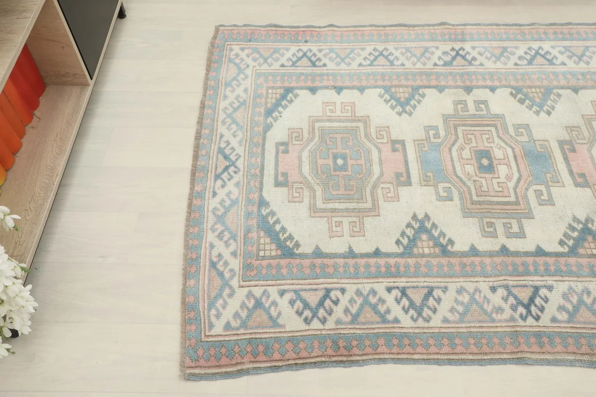 Angled shot of the rug on a light floor, with part of a wooden cabinet visible in the background.