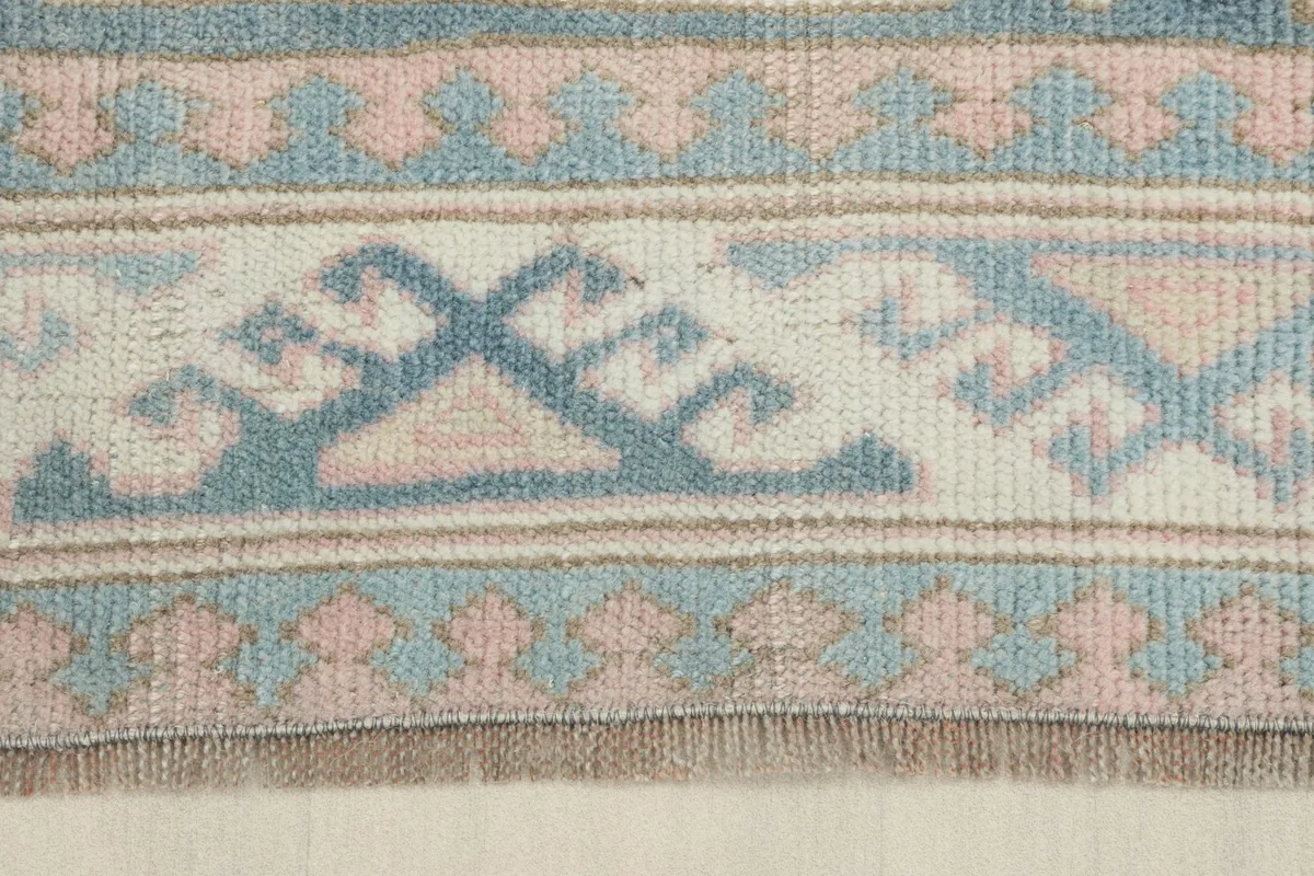 Detailed view of the rug's edge, showing the hand-knotted texture and color variations in the wool pile.