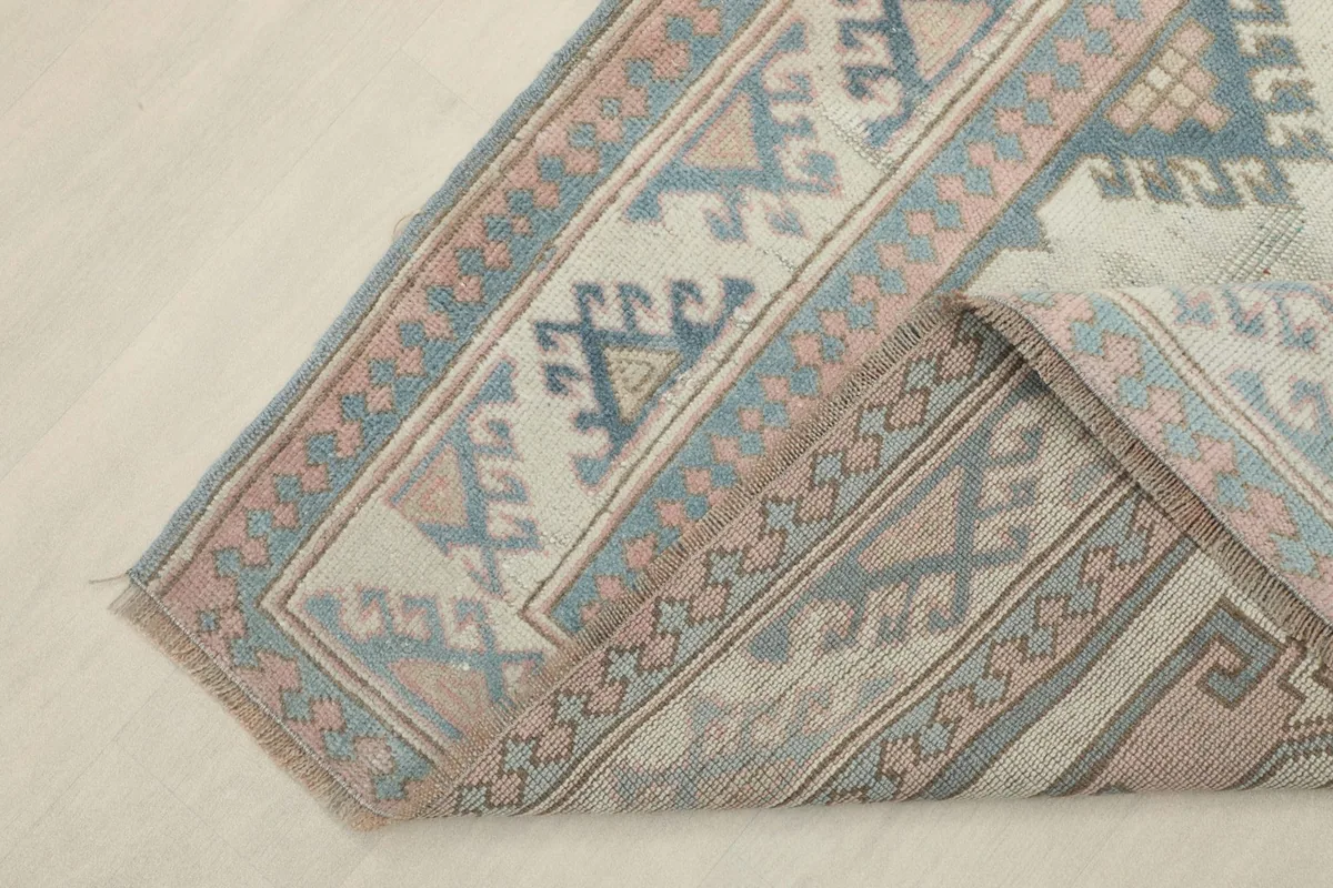 Corner of the rug folded back, revealing the reverse side of the hand-knotted cotton foundation.