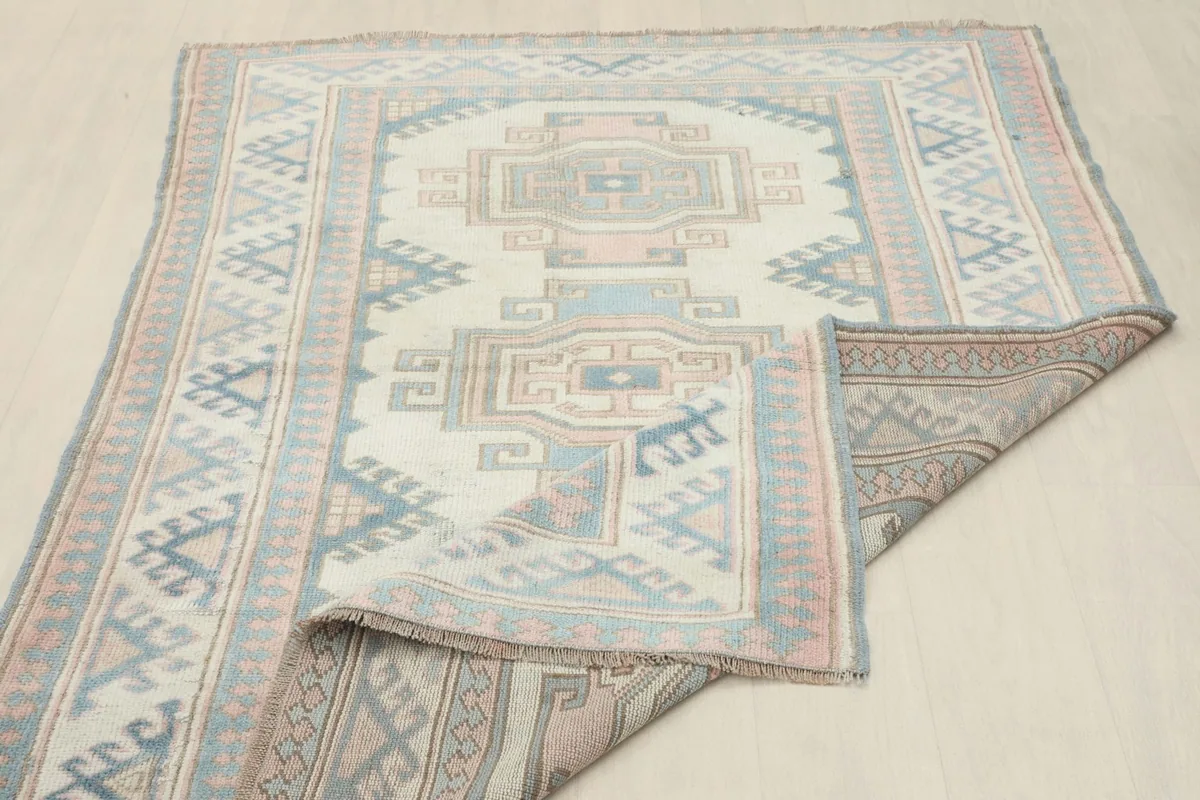 Rug partially folded, displaying the full design and the tightly woven cotton foundation.