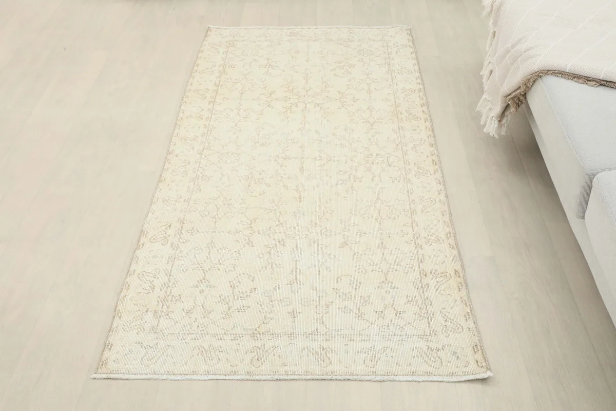 Full view of the soft ivory floral rug in a room, offering a perspective on its size and placement next to a sofa.
