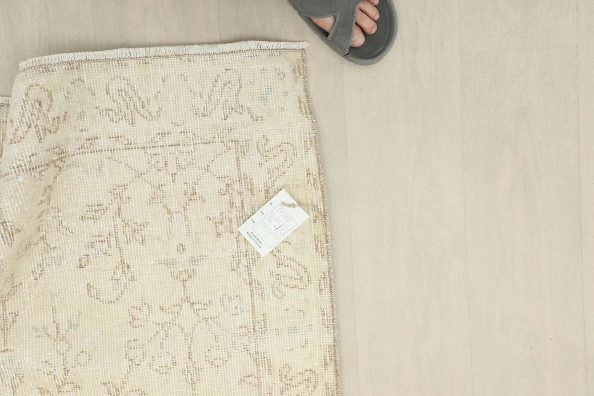 Overhead view of a foot next to the folded rug, providing a sense of scale for the 3x6 size.
