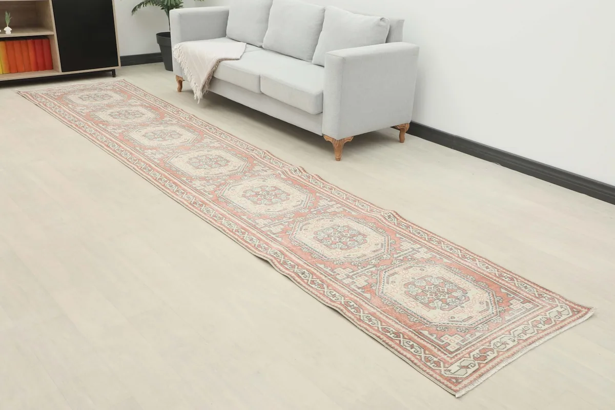 Angle view of the rose and ivory geometric runner rug extending along a light-colored floor in a living area