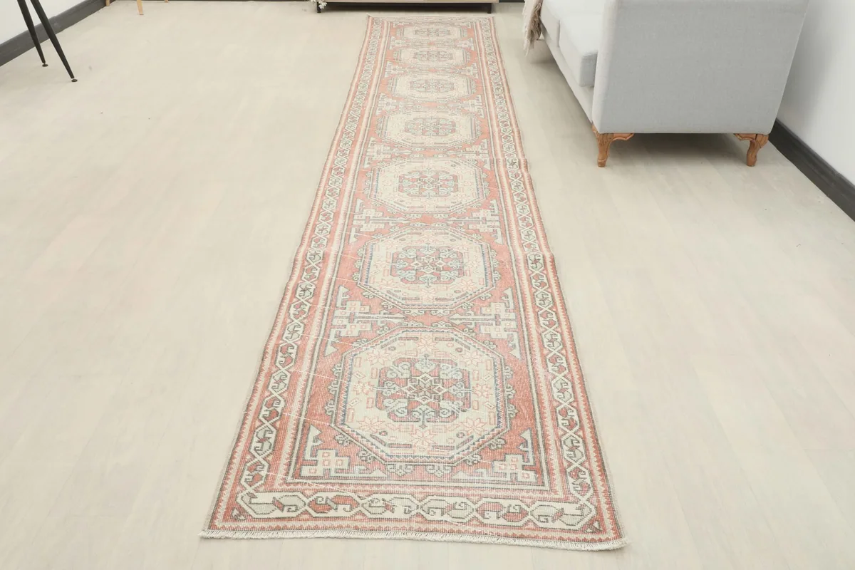 Full view of the rose and ivory runner rug in a room, emphasizing its long, narrow shape
