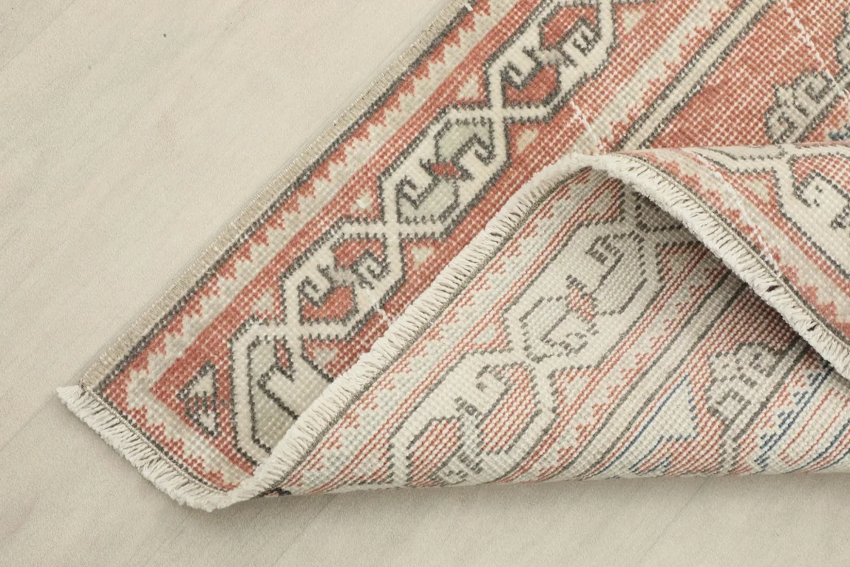 Corner of the runner rug folded back, showing the back of the rug and its construction