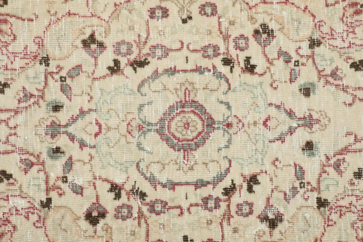 Close-up of the vintage rug's intricate medallion and faded rose and gray patterns