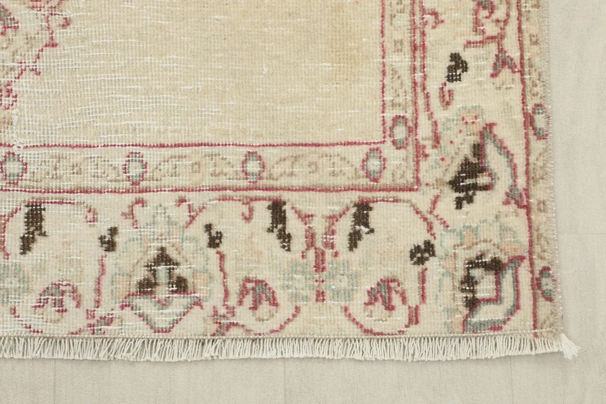 Detail of the rug's border design, fringe, and corner showing subtle wear
