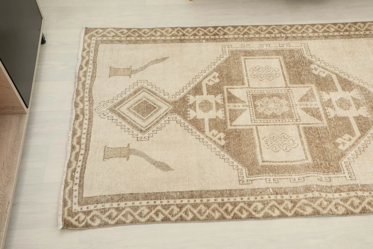 Close-up angled view of the end of the runner rug, showing beige field and border details