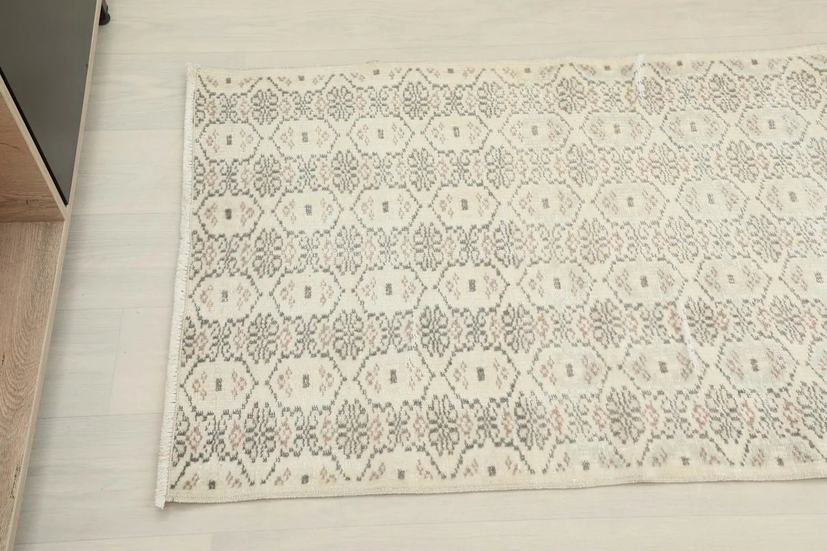 Overhead angled shot showing the repeating geometric motifs in gray and rust on the cream background