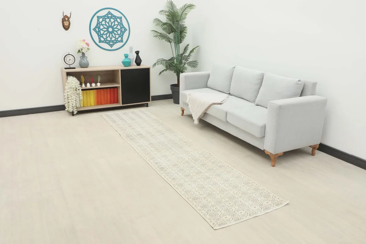 Long view of the cream runner rug in a modern living room setting with a light gray sofa