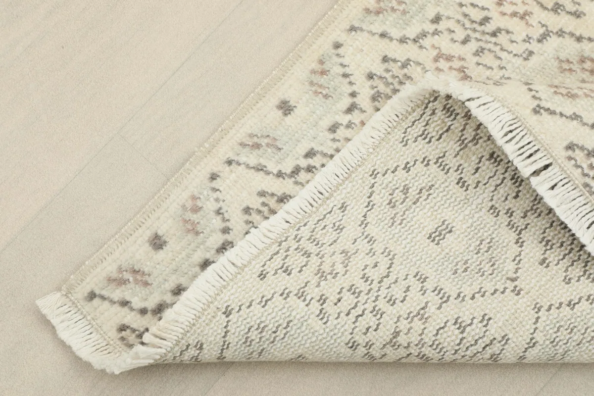 Corner of the rug folded to reveal the cotton foundation and the reverse side of the knotting