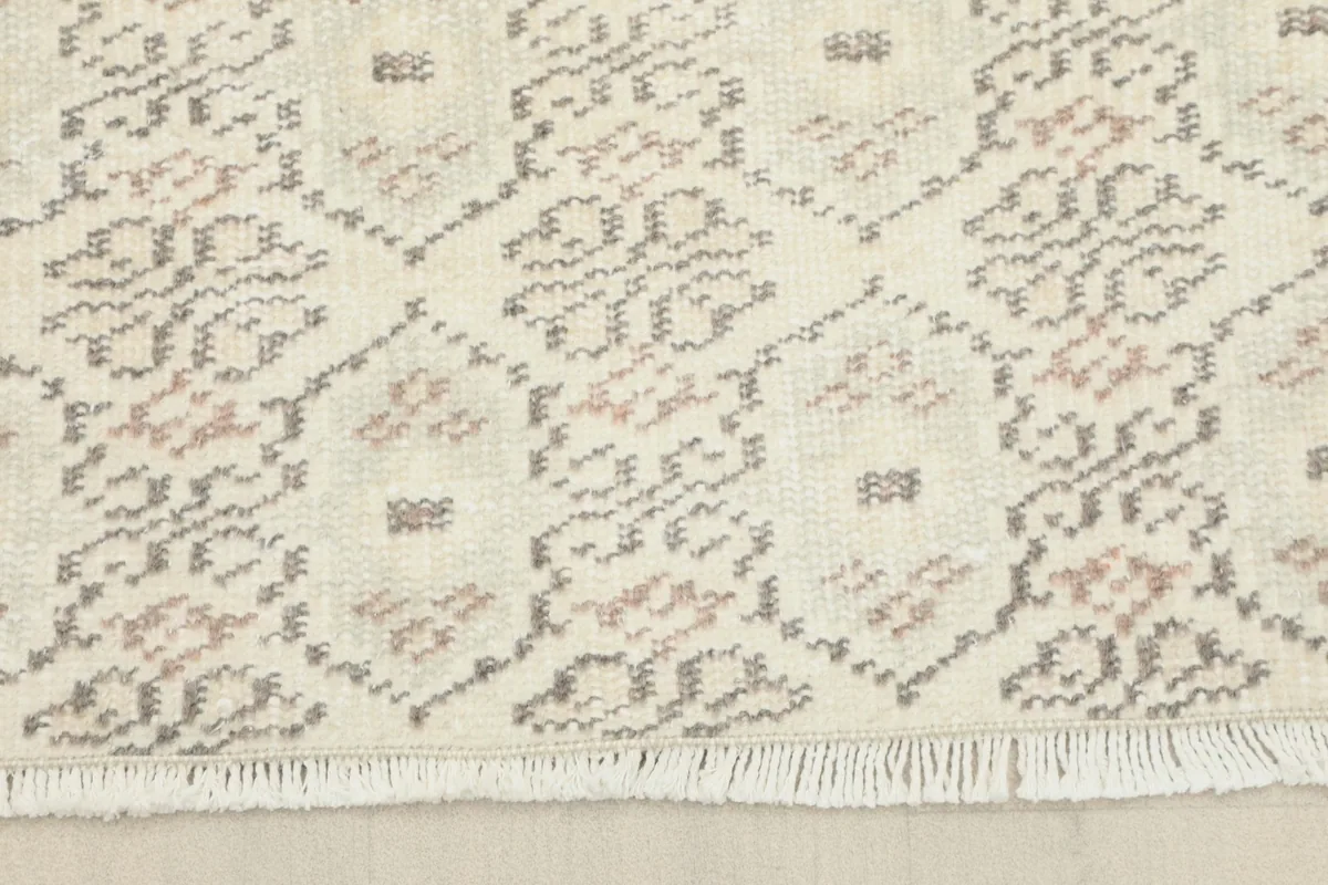 Detail of the rug's end with hand-knotted fringe and the geometric pattern extending to the edge