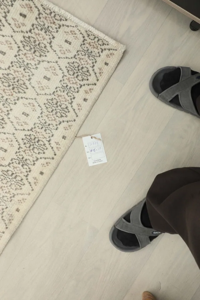 Overhead view of the rug next to a person's feet, showing scale and the pattern in a casual setting