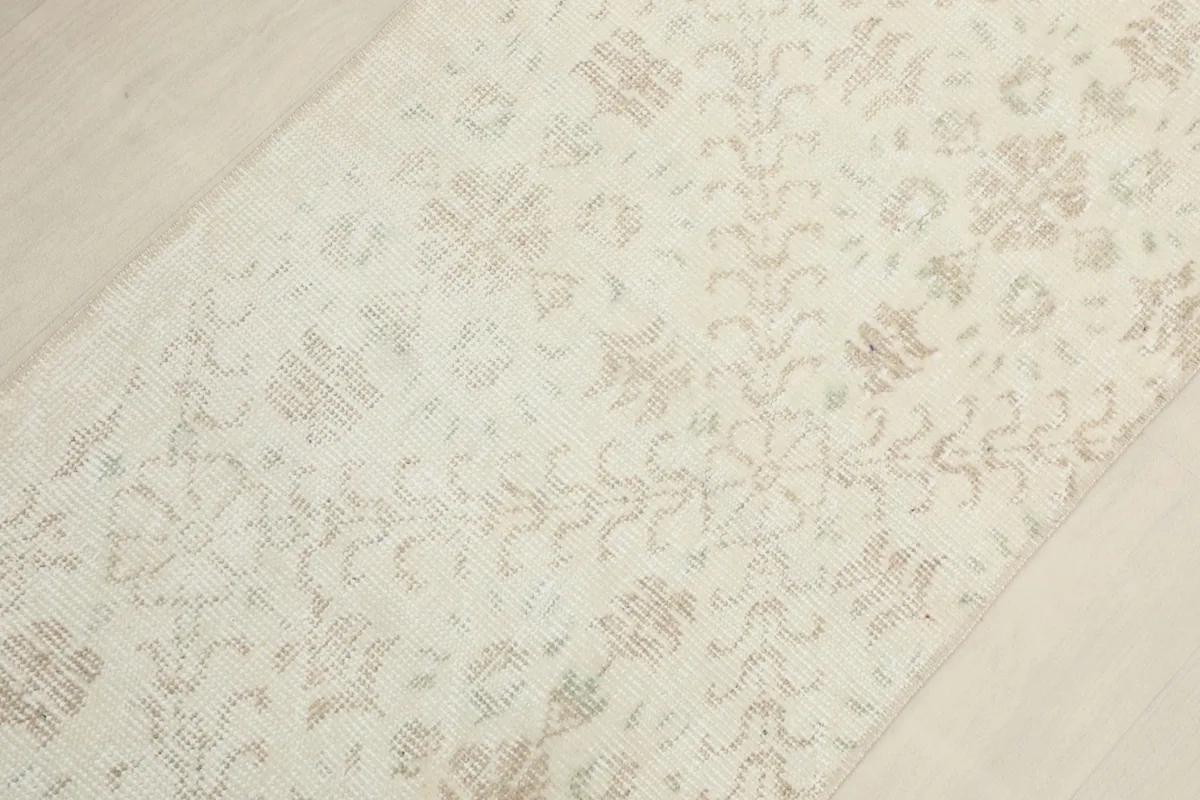 Overhead view showing the subtle, distressed look of the ivory field and beige motifs across the rug.