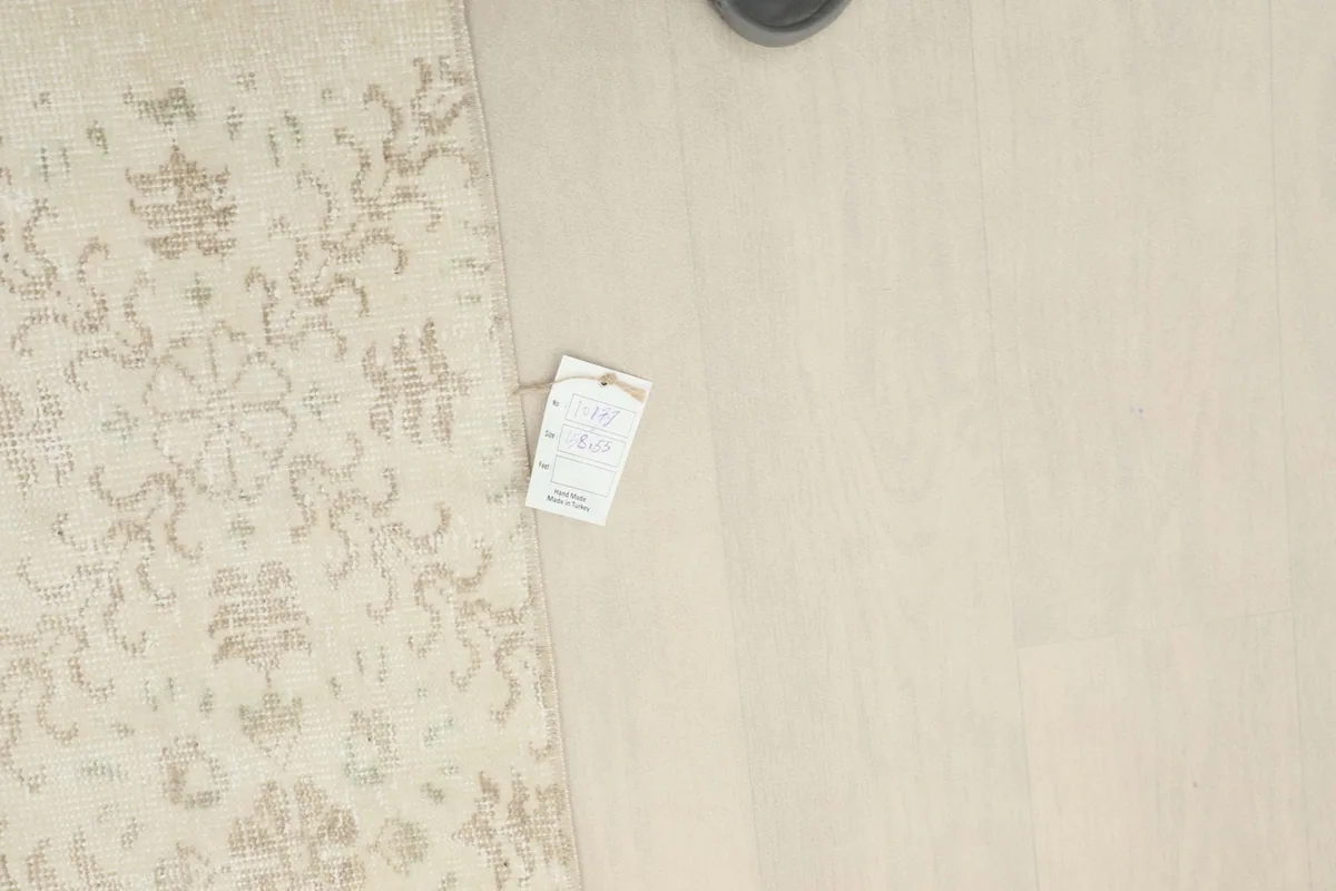 Overhead view of the rug with a size tag, showing the subtle patterns and overall condition.