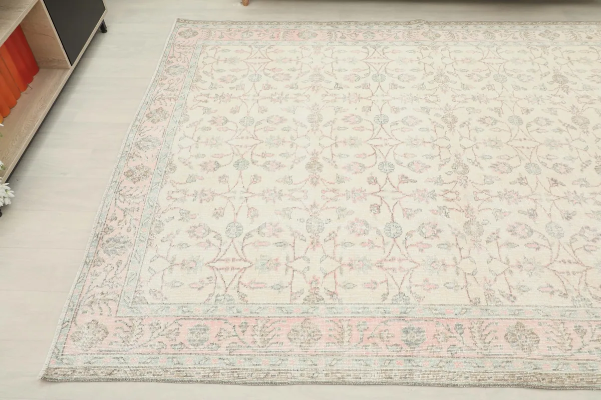 Angled shot of the rug's edge, focusing on the subtle rose and green tones in the border design.