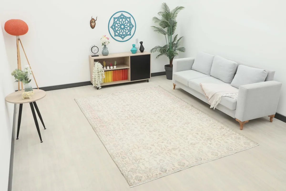 Vintage Anatolian rug with ivory field and floral motifs placed in a modern living room setting.