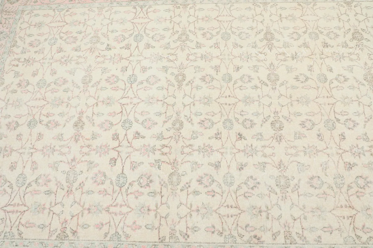 Detailed view of the rug's central field, showcasing the intricate ivory and rose floral motifs.