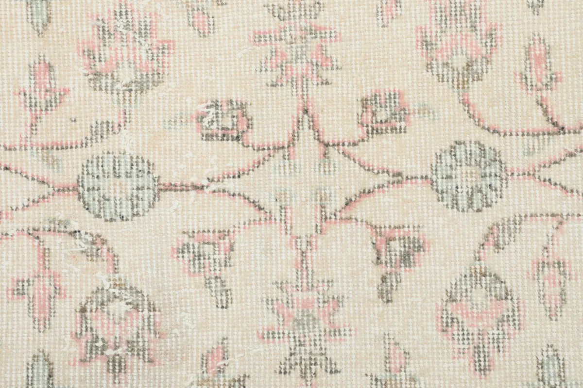 Close-up of the hand-knotted wool pile, revealing the texture and faded colors of the floral pattern.