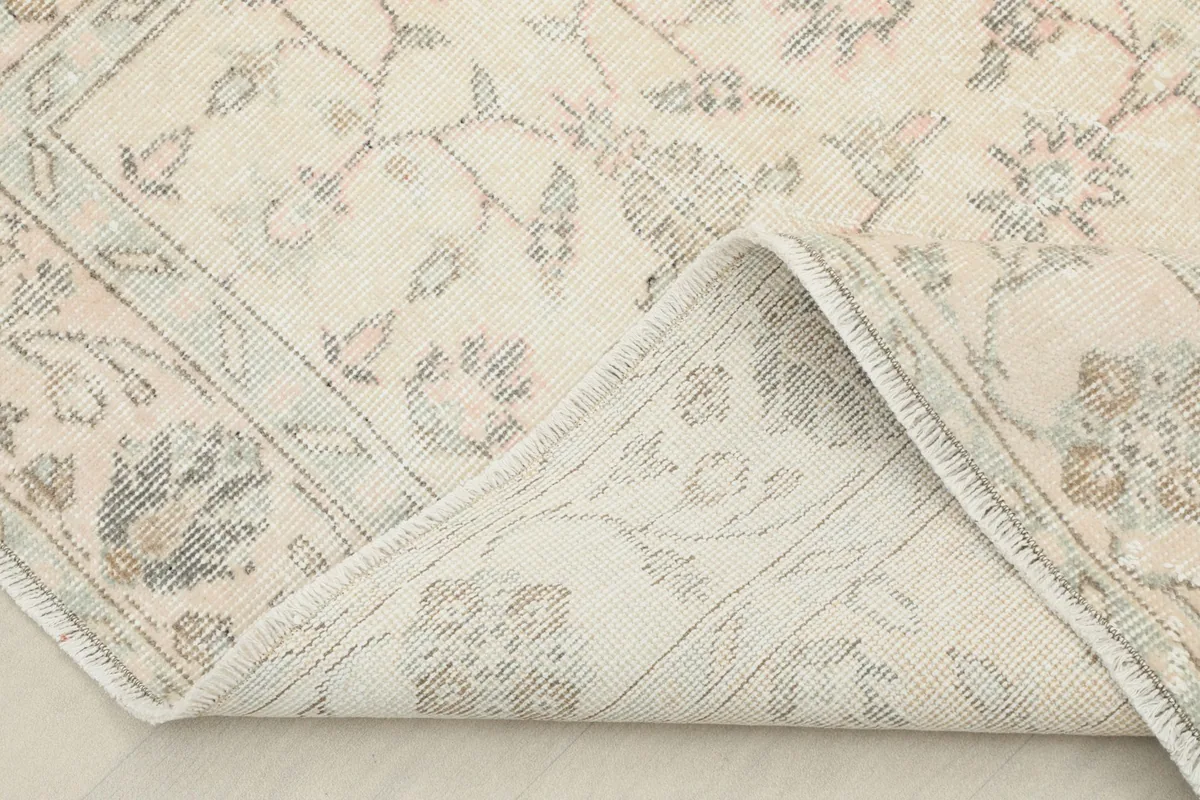 Corner of the rug folded back to show the cotton foundation and the reverse side of the hand-knotting.